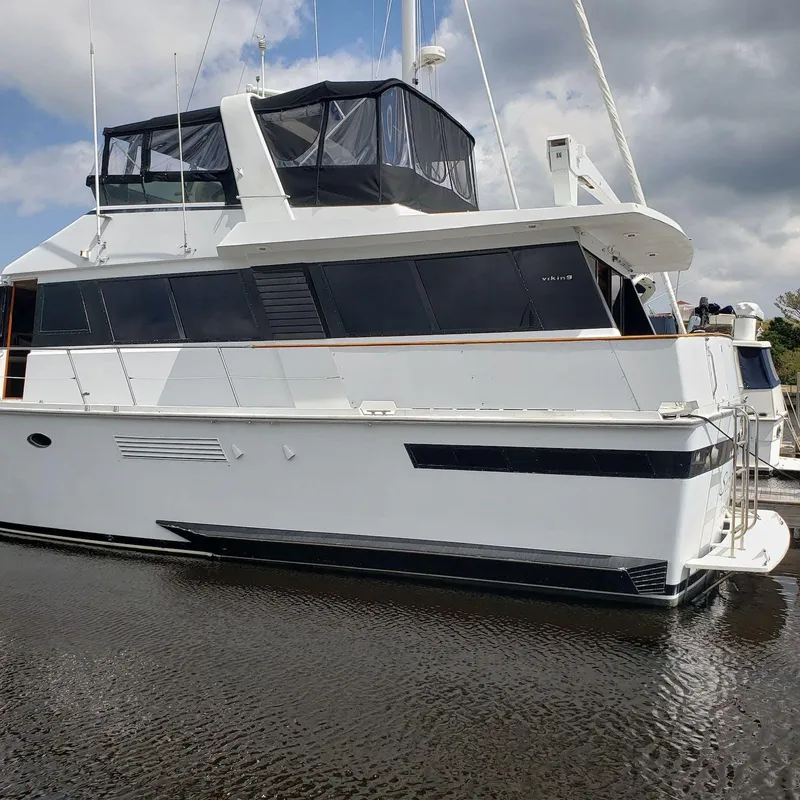 Slide: The Image of 1988 Viking 55 Motoryacht Walkaround, white exterior, docked on calm water under cloudy sky. - 7