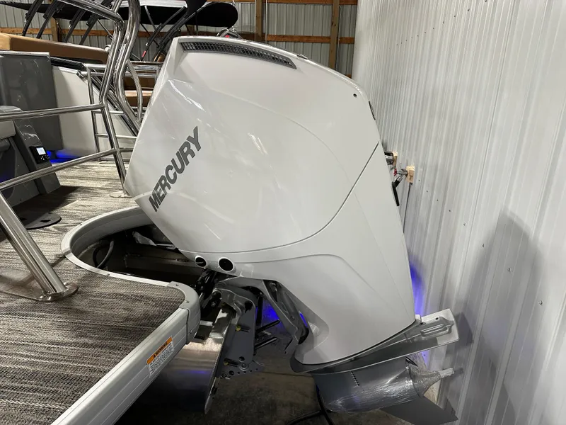 Slide: The Image of 2025 Godfrey AquaPatio 255 SFLW with Mercury outboard motor in a storage facility. - 12