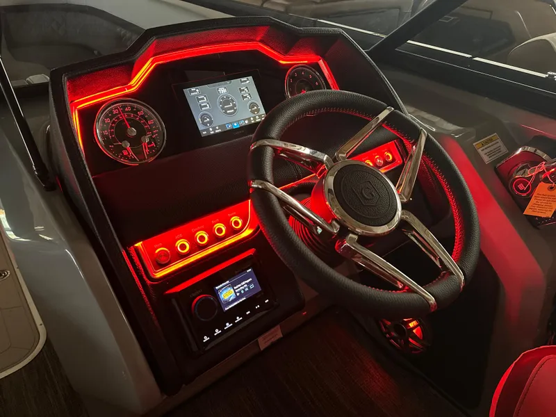 Slide: The Image of Dashboard of 2025 Godfrey AquaPatio 255 SFLW boat with illuminated controls and steering wheel. - 43