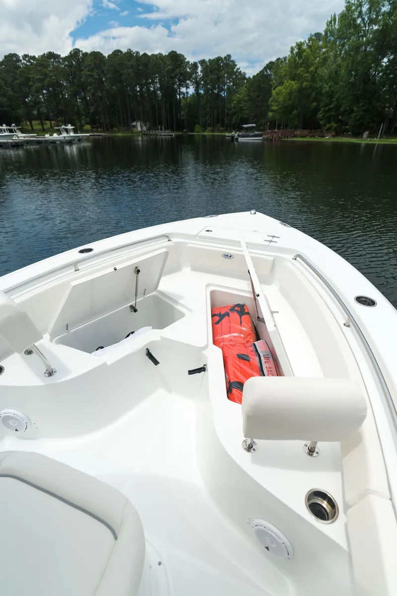 Slide: The Image of 2025 Sea Hunt Ultra 229 boat with open storage compartments on a calm lake. - 21