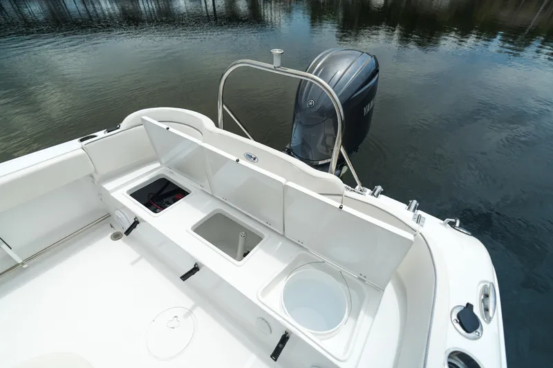 Slide: The Image of 2025 Sea Hunt Ultra 229 boat with open storage compartments and outboard motor. - 23