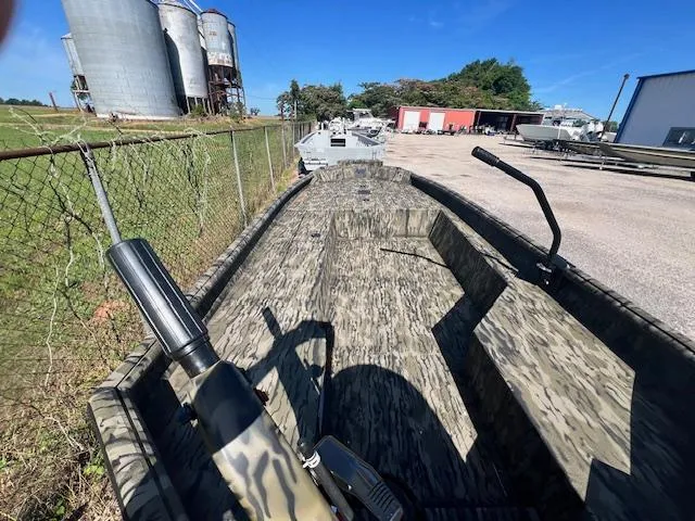 Slide: The Image of 2025 SeaArk 1752 Slayer Pro boat with camouflage design, parked near industrial silos. - 6