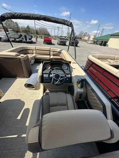 Slide: The Image of 2023 Godfrey Ap255sdc boat interior with steering console and seating under a clear sky. - 9