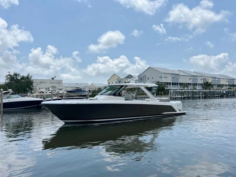 Slide: The Image of 2023 Tiara Yachts 38 LS cruising on a sunny day near waterfront homes. - 2