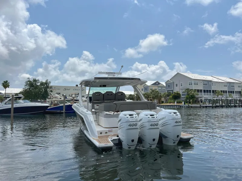 Slide: The Image of 2023 Tiara Yachts 38 LS with triple outboard engines docked in a marina. - 4