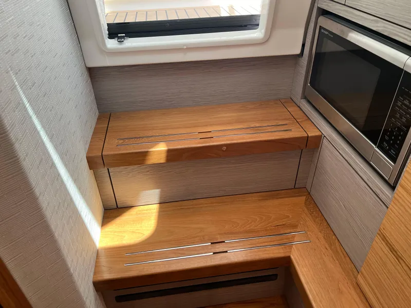 Slide: The Image of 2023 Tiara Yachts 38 LS interior with wooden steps and built-in microwave. - 43