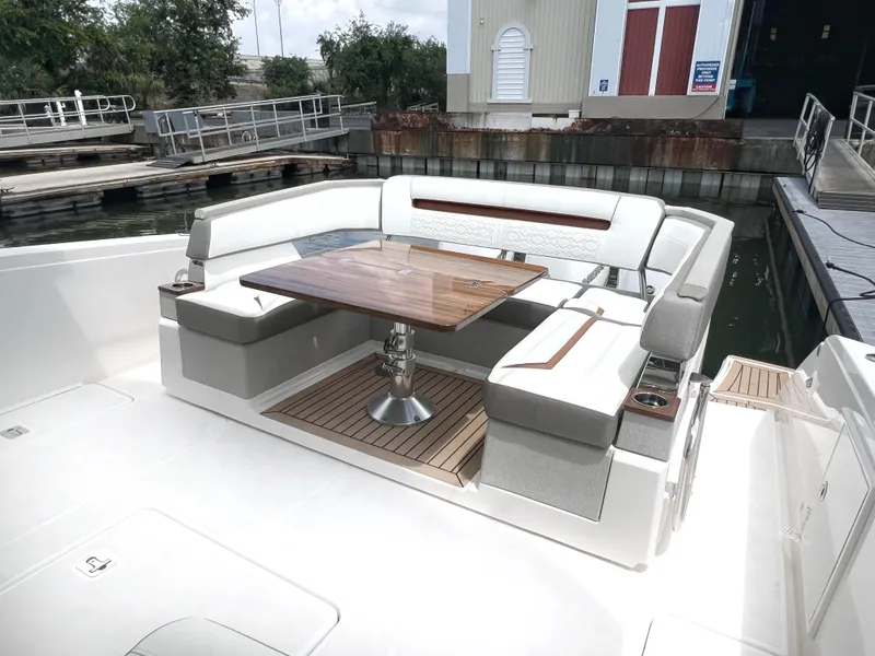 Slide: The Image of 2023 Tiara Yachts 38 LS boat with elegant seating and wooden table at dock. - 9