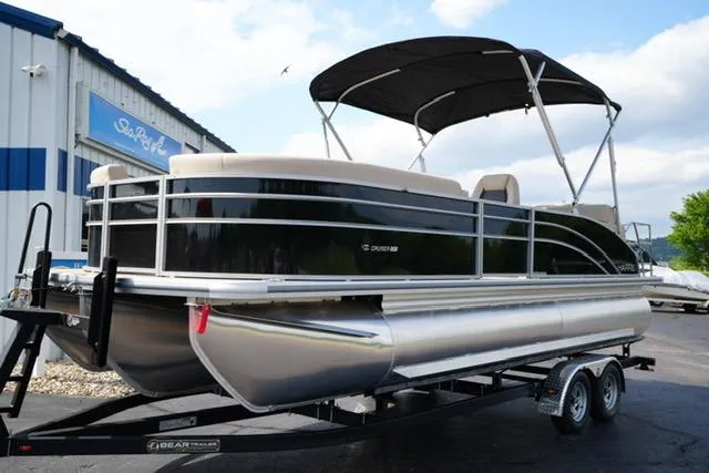 Slide: The Image of 2025 Harris Cruiser 230 pontoon boat on trailer, parked outside dealership. - 1