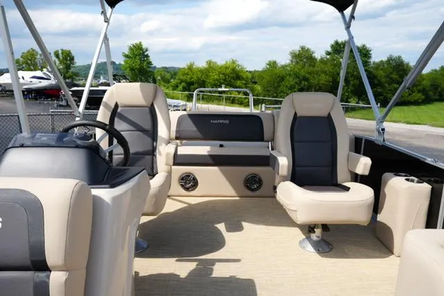 Slide: The Image of 2025 Harris Cruiser 230 pontoon boat interior with beige and black seating, steering wheel, and open canopy. - 12