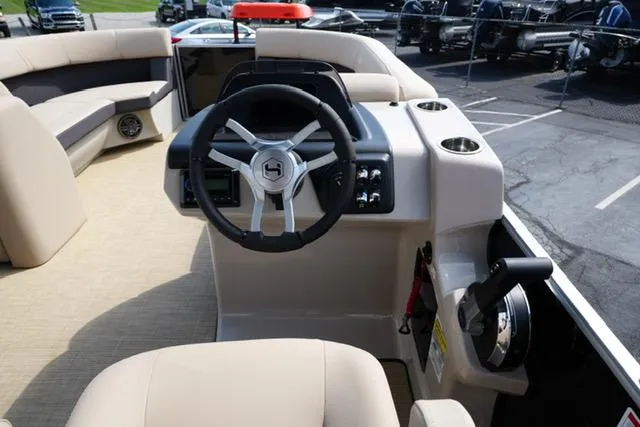 Slide: The Image of 2025 Harris Cruiser 230 boat interior with steering wheel and beige seating. - 14