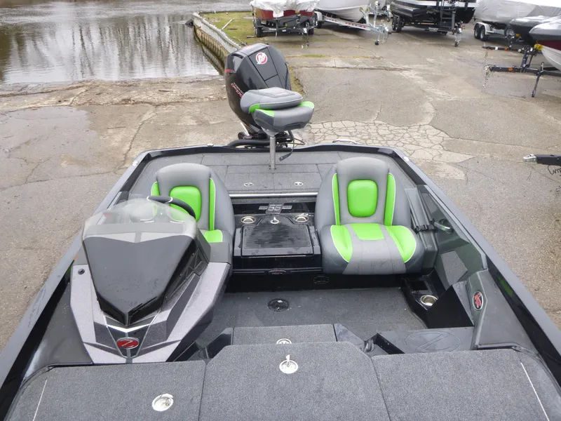 Slide: The Image of 2023 Ranger Z518 boat interior with green and gray seats, docked near water. - 9