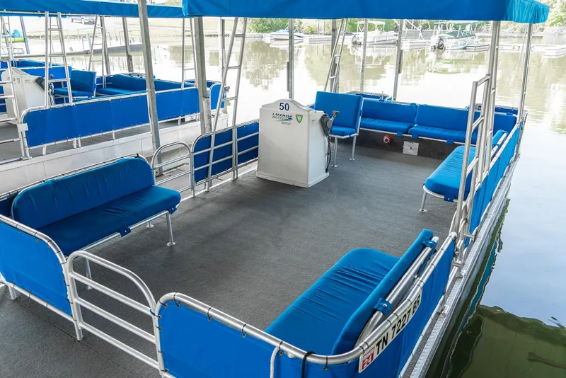 Slide: The Image of Pontoon boat with blue seating, Custom Lake Wind 25 x 10, year 2000, docked on calm water. - 10