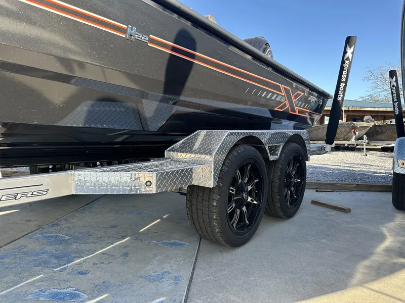 Slide: The Image of 2025 Xpress Hyper-Lift Series H22B boat on a dual-axle trailer, featuring sleek design and black wheels. - 2
