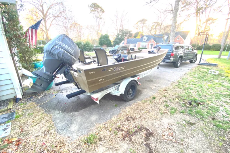 Slide: The Image of Boat on trailer with Yamaha motor, parked in driveway, surrounded by trees and houses. - 8