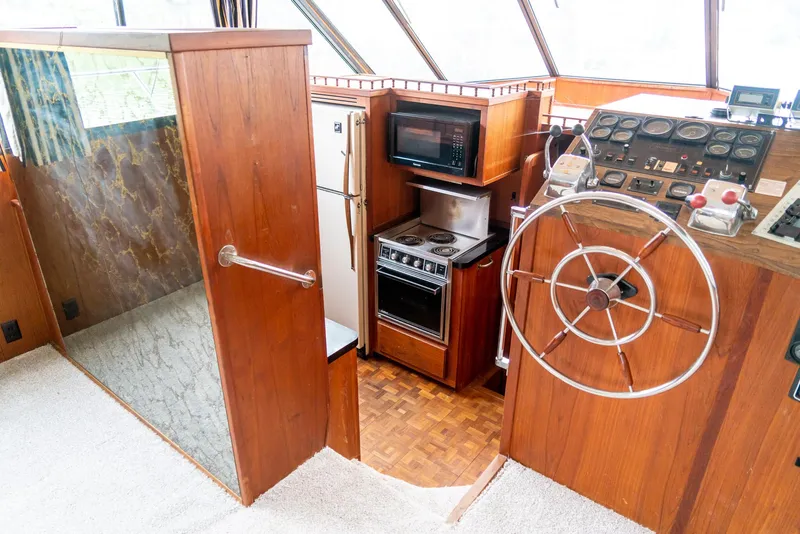 Slide: The Image of 1985 Bluewater 46 Motor Yacht interior with kitchen and helm, featuring wood paneling and appliances. - 16