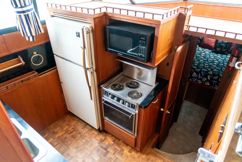 Slide: The Image of 1985 Bluewater 46 Motor Yacht kitchen with stove, microwave, and refrigerator. - 17