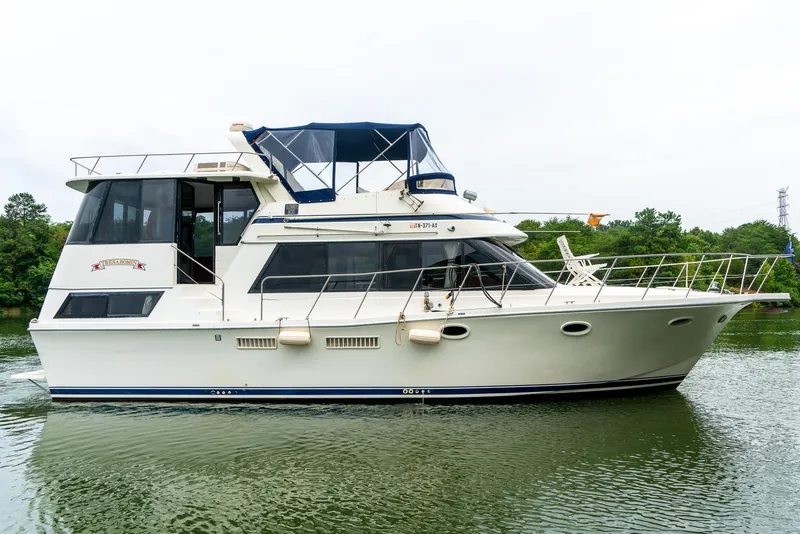Slide: The Image of 1985 Bluewater 46 Motor Yacht on calm water, featuring a sleek design and spacious deck. - 4