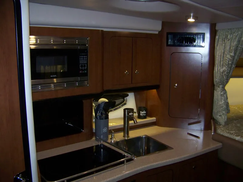 Slide: The Image of Interior of 2020 Crownline 350 SY yacht featuring a modern kitchen with wood cabinetry. - 21
