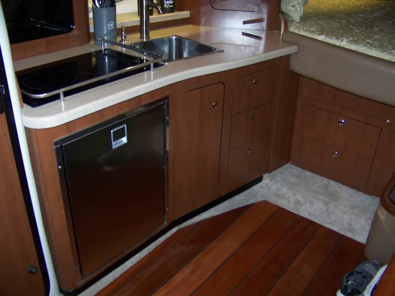 Slide: The Image of 2020 Crownline 350 SY yacht interior with kitchenette, featuring wood cabinetry and stainless steel appliances. - 22