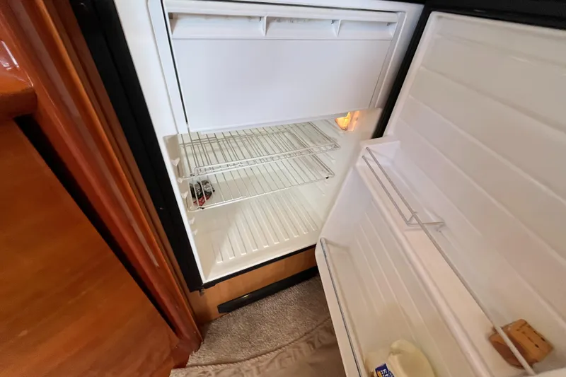 Slide: The Image of Open refrigerator inside 2006 Azimut Atlantis yacht, showing empty shelves and door compartments. - 27