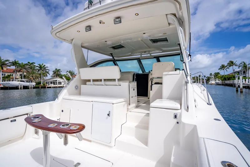 Slide: The Image of 2005 Tiara Yachts 4200 Open, spacious deck, luxurious seating, docked by palm-lined waterfront. - 42