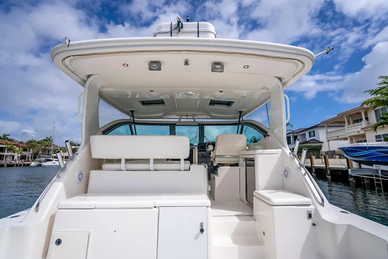 Slide: The Image of 2005 Tiara Yachts 4200 Open, spacious deck view, docked by waterfront homes under blue sky. - 43