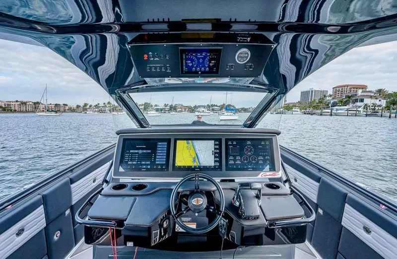 Slide: The Image of 2023 Cigarette 41 Nighthawk boat cockpit with advanced navigation displays on a calm waterway. - 2