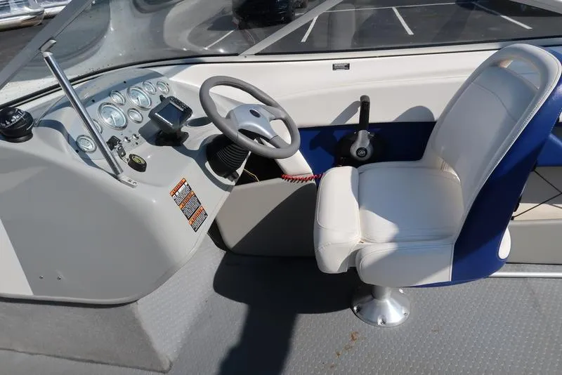 Slide: The Image of 2009 Bayliner 215 BR boat cockpit with steering wheel and white captain's chair. - 12
