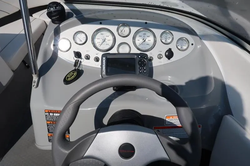 Slide: The Image of Dashboard of a 2009 Bayliner 215 BR boat with steering wheel and gauges. - 13
