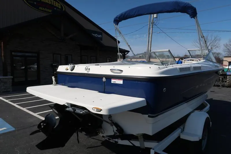 Slide: The Image of 2009 Bayliner 215 BR boat on trailer, parked outside a marine store. - 2