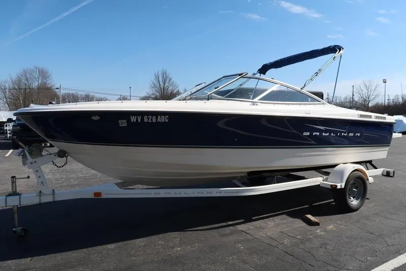 Slide: The Image of 2009 Bayliner 215 BR boat on trailer, parked outdoors under clear sky. - 4