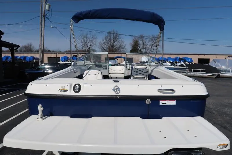 Slide: The Image of 2009 Bayliner 215 BR boat with blue and white exterior, parked outdoors. - 5