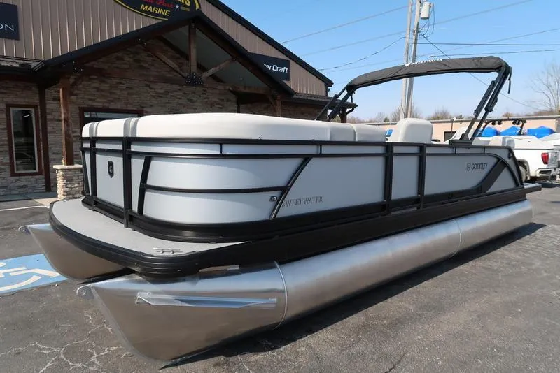 Slide: The Image of 2025 Godfrey Sweetwater 2286 QS pontoon boat parked outside a marine dealership. - 4