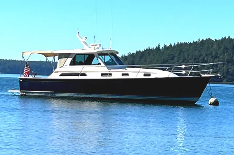 Slide: The Image of 2007 Sabre 38 Hardtop Express yacht anchored on calm water with forested shoreline. - 1