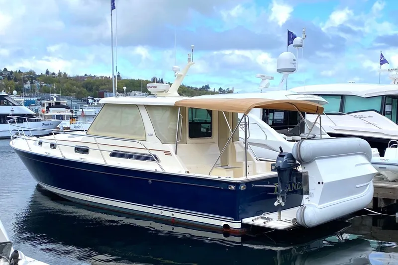 Slide: The Image of 2007 Sabre 38 Hardtop Express yacht docked at marina, blue hull, beige canopy. - 2
