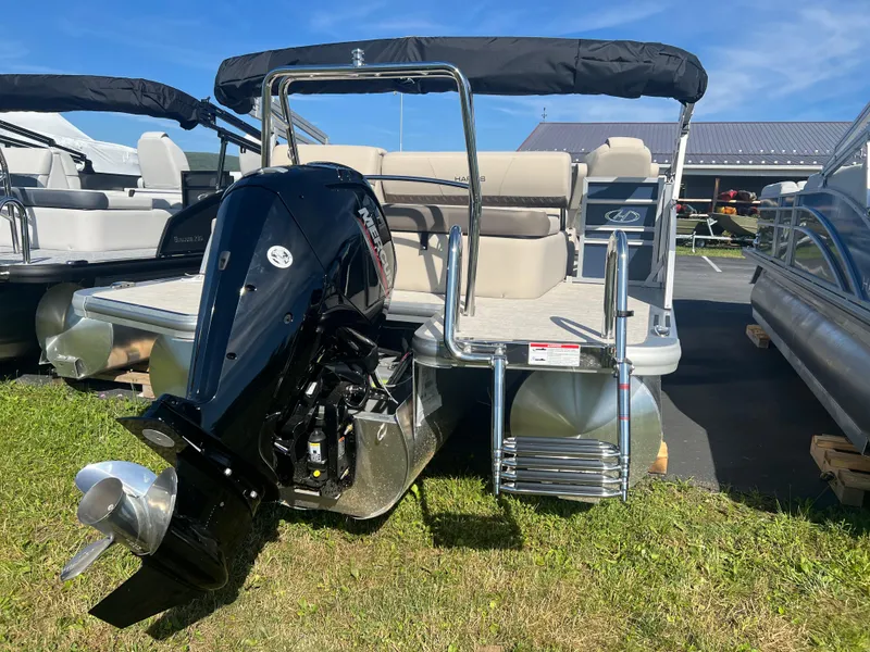 Slide: The Image of 2024 Harris FloteBote Sunliner 230 pontoon boat with outboard motor, parked on grass. - 20