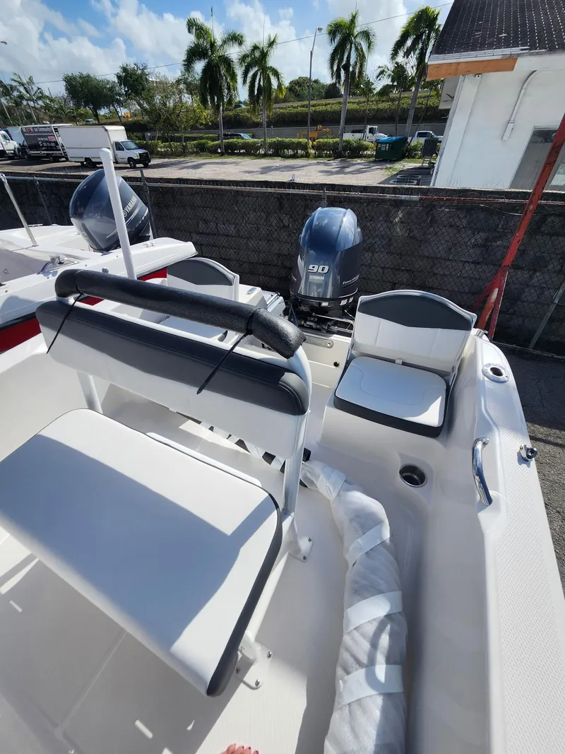 Slide: The Image of 2025 Robalo R160 boat interior with seating and outboard motor, parked outdoors. - 7