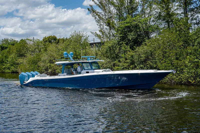 Slide: The Image of 2023 HCB 53 Sueños boat cruising on a scenic waterway with lush greenery. - 1