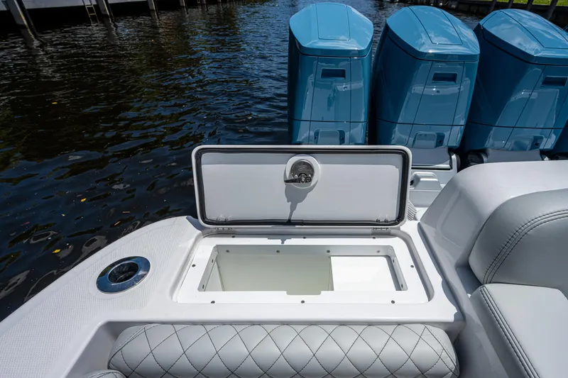 Slide: The Image of 2023 HCB 53 Sueños boat with open storage compartment and triple outboard engines. - 16