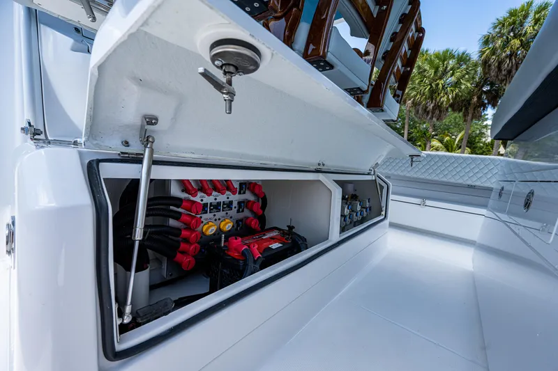 Slide: The Image of 2023 HCB 53 Sueños boat storage compartment with electrical components, open hatch, and palm trees in background. - 31