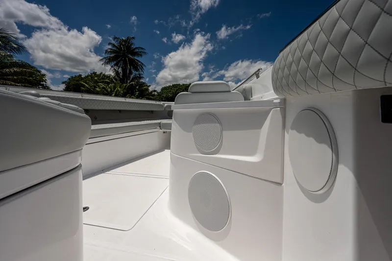 Slide: The Image of 2023 HCB 53 Sueños boat interior with speakers, white seating, and blue sky background. - 41