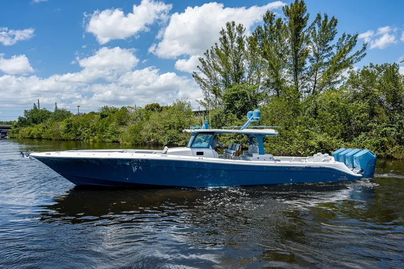 Slide: The Image of 2023 HCB 53 Sueños boat cruising on a sunny day, surrounded by lush greenery. - 6