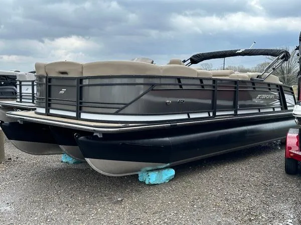 The Image of 2023 Starcraft CX25DL Bar pontoon boat on gravel, under cloudy sky. - 1