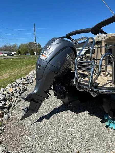 Slide: The Image of 2023 Starcraft CX25DL Bar boat with powerful 300 V6 engine, parked on gravel. - 10