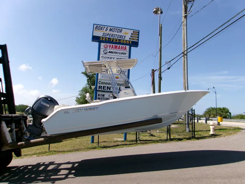 Slide: The Image of 2025 Key West 203 FS boat on forklift near Boat & Motor Superstores sign. - 0