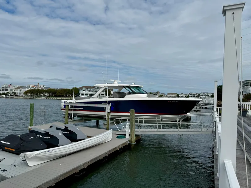 Slide: The Image of 2022 Tiara Yachts 43 LS docked at a marina under a cloudy sky. - 11
