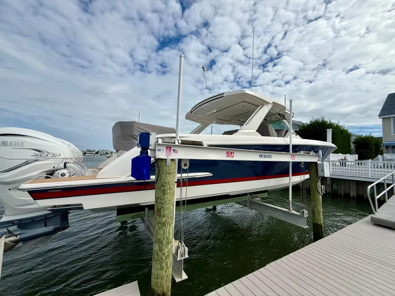 Slide: The Image of 2022 Tiara Yachts 43 LS on a lift at a marina, under a cloudy sky. - 7