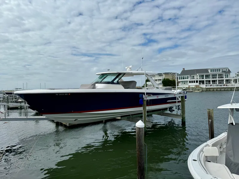 Slide: The Image of 2022 Tiara Yachts 43 LS docked in a marina under a cloudy sky. - 9