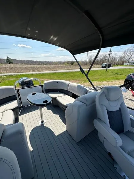 Slide: The Image of 2023 Starcraft SLS-3 pontoon boat interior with plush seating and table under canopy. - 8