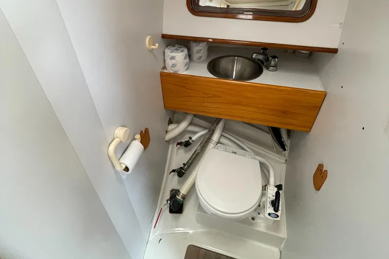 Slide: The Image of 1991 Beneteau Oceanis 390 yacht bathroom with sink, toilet, and wooden cabinetry. - 12
